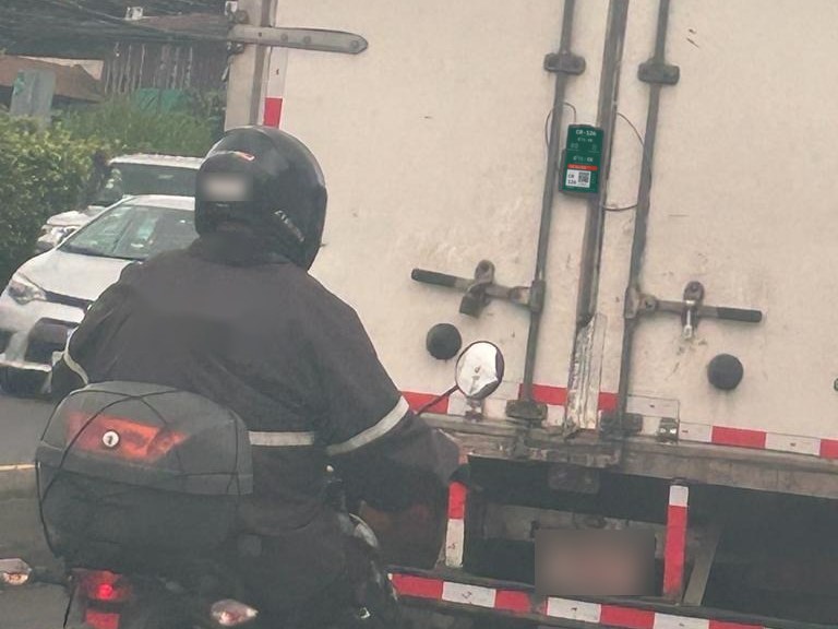 Custodio en motocicleta escoltando un camión con marchamo electrónico en la puerta